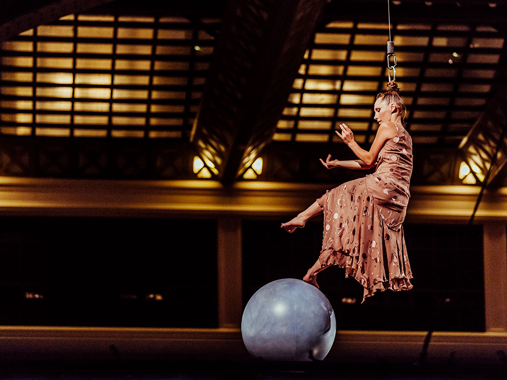 Une artiste de circque tractée par les cheveux marchant sur une boule géante