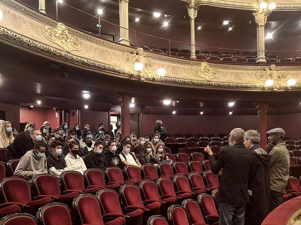 Des élèves discutent dans la grande salle avec le metteur en scène