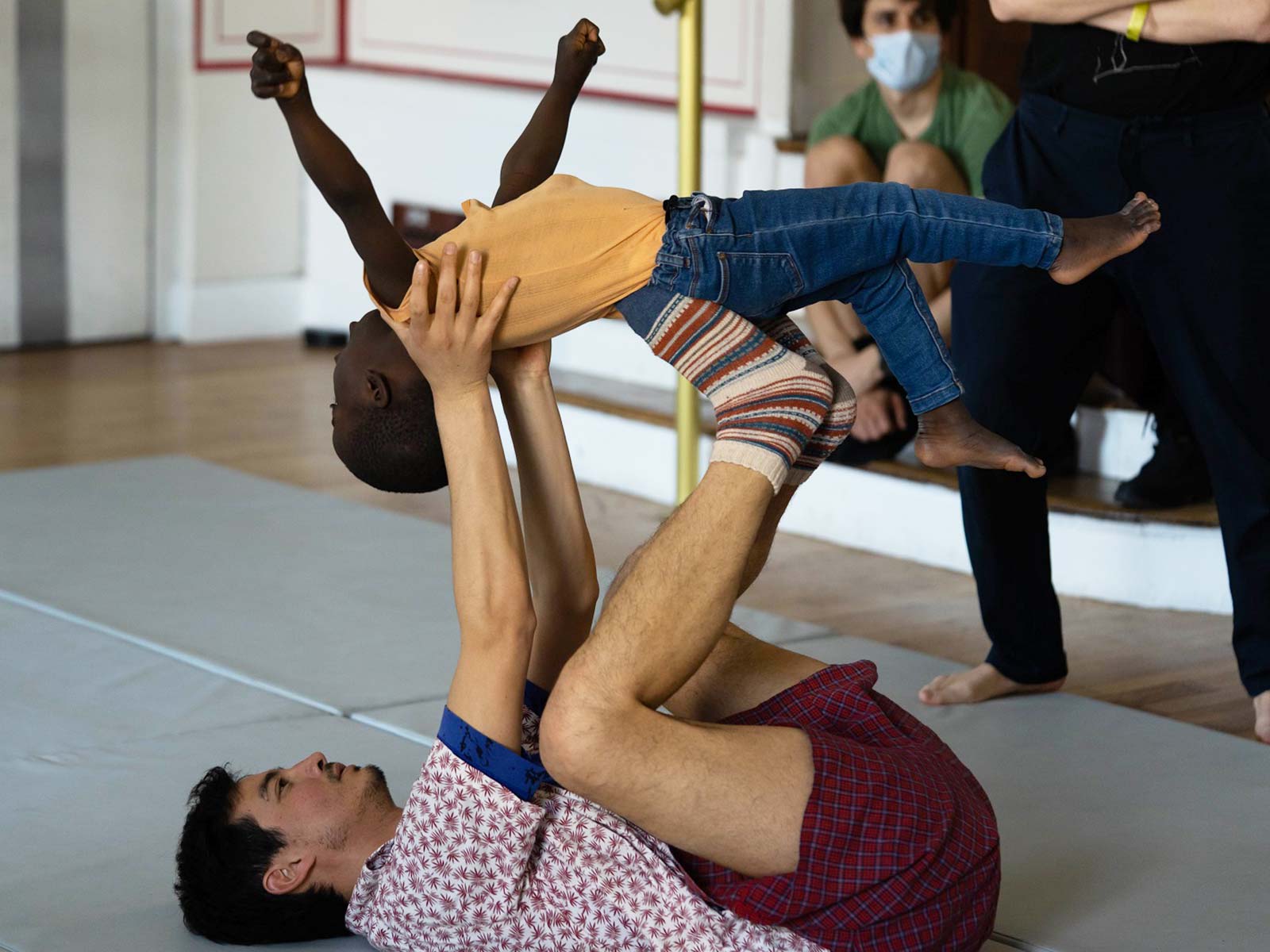 Un danseur tient un petit enfant au-dessus de lui