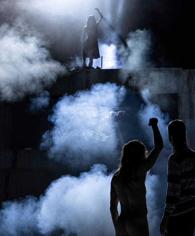 des danseurs le poing levé en contre jour et dans un halo de fumée