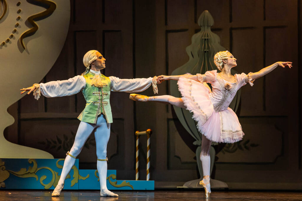 Un danseur tient par la main une danseuse sur pointe, en costumes XVIIIe siècle