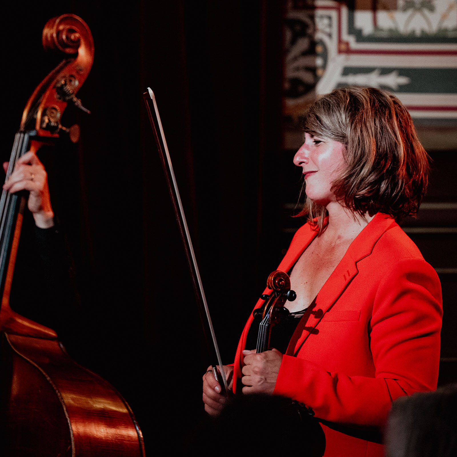 Une femme en veste rouge tenant un violon